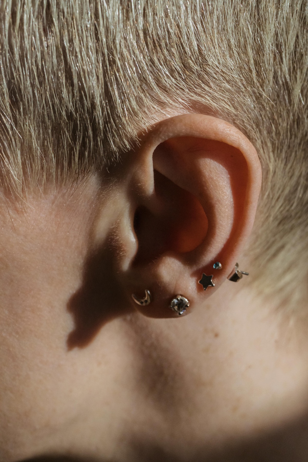 Ear close-up with star and crescent-shaped lobe studs