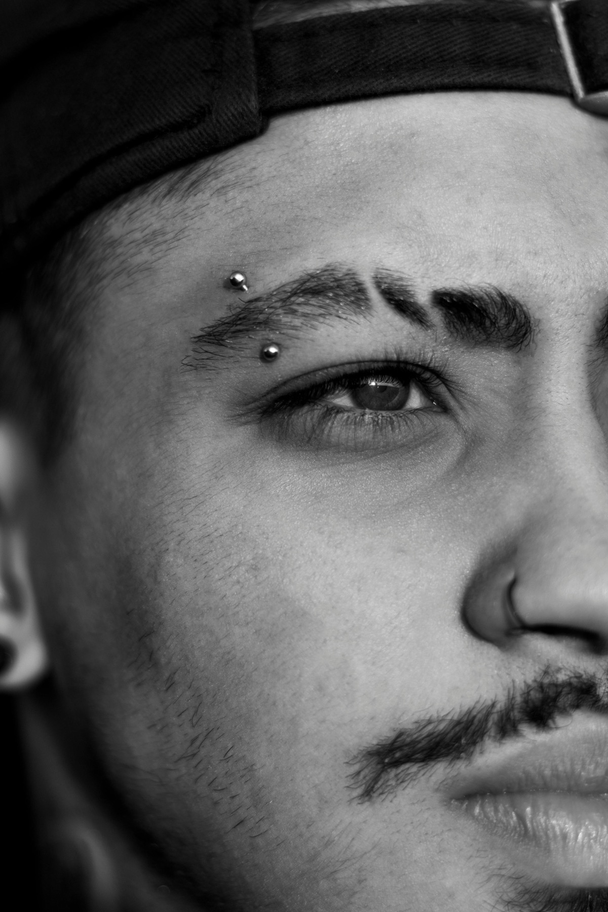 Black-and-white portrait with an eyebrow piercing and nose ring